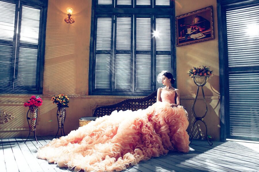 women in luxurious peach ruffled dressed sitting in a sunroom
